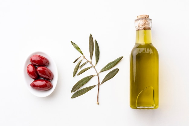 Bottiglia di olio d'oliva con foglie e olive rosse