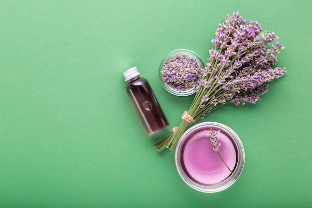 Bottiglia di olio essenziale di lavanda su sfondo di colore verde aromaterapia fresca di fiori di lavanda