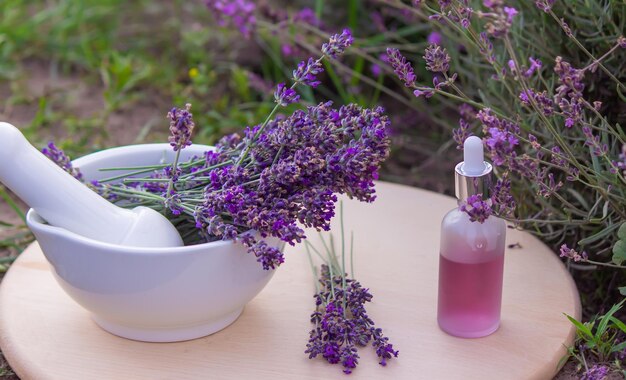 Bottiglia di olio essenziale di lavanda su tavola di legno e sfondo di campo di fiori