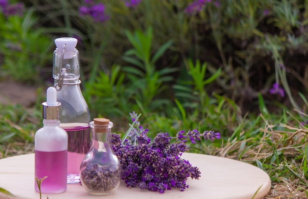 Bottiglia di olio essenziale di lavanda su tavola di legno e sfondo di campo di fiori