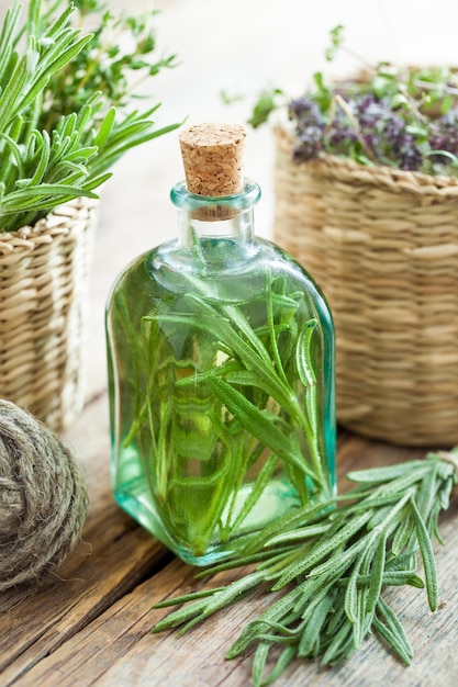 Bottiglia di olio essenziale di rosmarino o infusione e cesto con primo piano di erbe curative