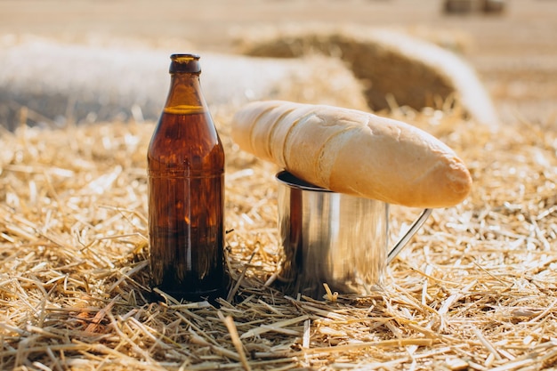 Bottiglia di pane alla birra e boccale di metallo su sfondo di campo di grano