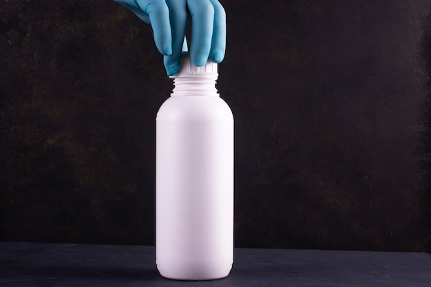 Bottiglia di plastica bianca per pesticidi su uno sfondo scuro