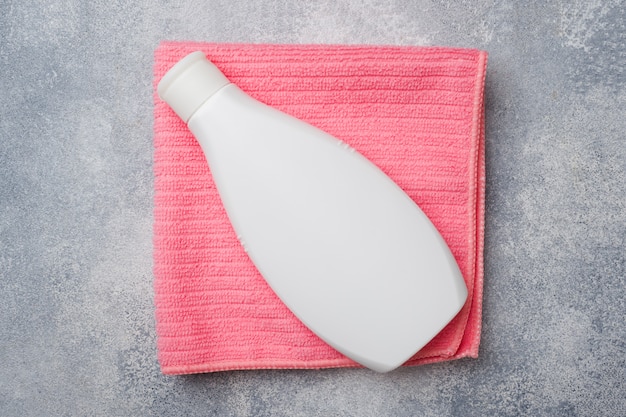Bottiglia di plastica bianca su un asciugamano rosa, accessori per il bagno,