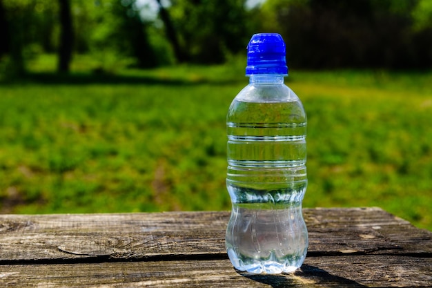 Bottiglia di plastica con acqua chiara su tavola di legno rustica