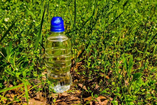 Bottiglia di plastica con l'acqua limpida nell'erba verde