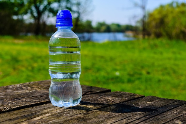 Bottiglia di plastica con l'acqua limpida sul tavolo di legno