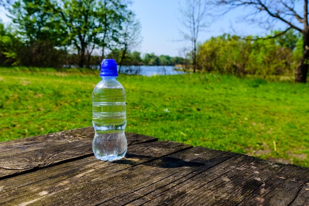 Bottiglia di plastica con l'acqua limpida sul tavolo di legno