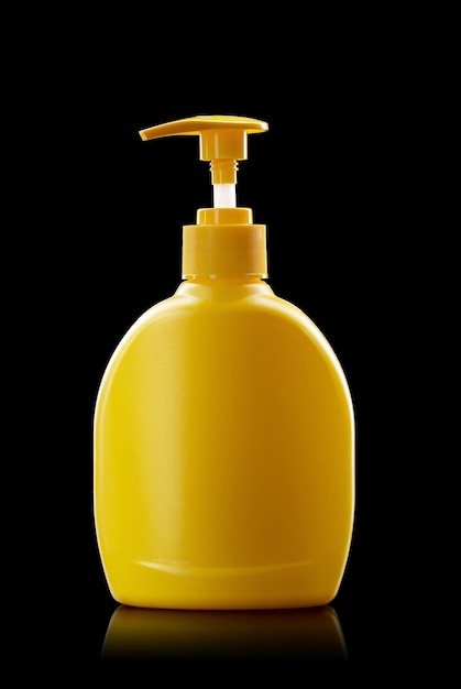 Bottiglia di plastica gialla della pompa isolata su una priorità bassa nera. distributore di disinfezione mani, concetto di igiene personale.