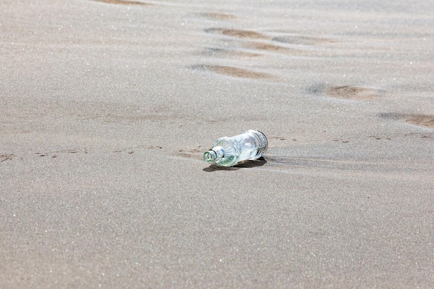 Bottiglia di plastica sulla spiaggia. Concetto di inquinamento dell'ambiente.