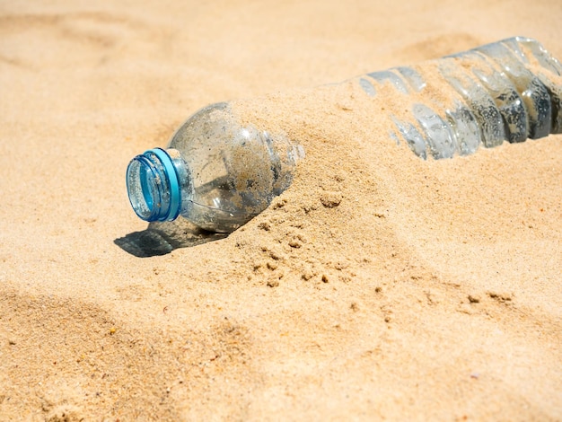 Bottiglia di plastica sulla spiaggia sabbiosa Primo piano bottiglie di acqua potabile di plastica usate senza tappo impilate con sabbia scaricata sulla spiaggia Rifiuti inquinati abbandonati dai turisti