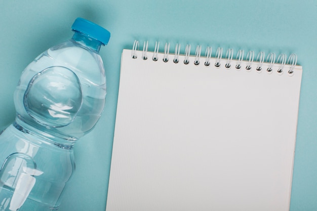 Bottiglia di plastica vista dall'alto di acqua e blocco note dello spazio della copia