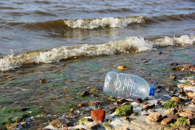 Bottiglia di plastica vuota sulle onde vicino alla riva. immondizia, rifiuti, inquinamento e natura. t