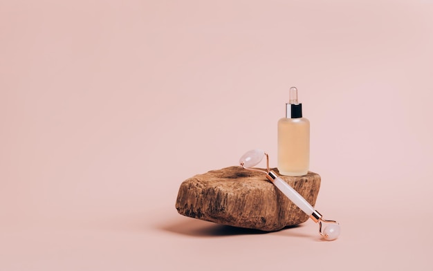 Bottiglia di prodotto cosmetico massaggio a rullo gua sha sfondo rosa podio astratto