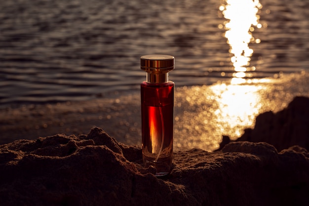 Bottiglia di profumo al tramonto sulla spiaggia