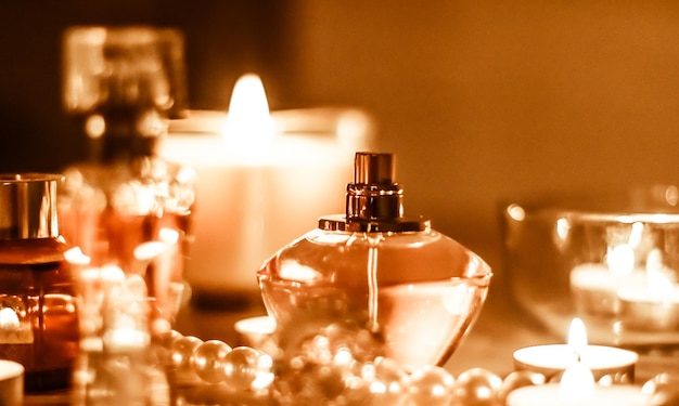 Bottiglia di profumo e fragranze vintage sul tavolo da toeletta glamour di notte perle gioielli e eau de parfum come regalo di vacanza marchio di bellezza di lusso presente