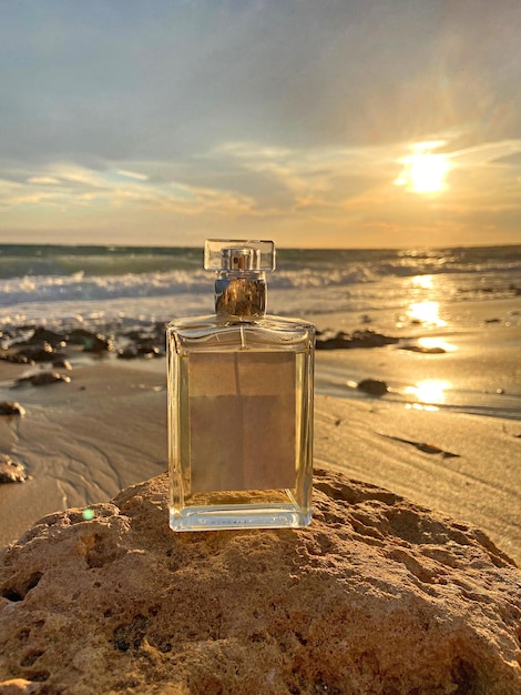 Bottiglia di profumo in una vista panoramica del mare contro il cielo durante il tramonto