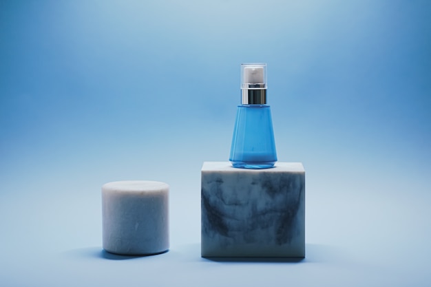 Bottiglia di siero e barattolo di crema per il viso su sfondo blu prodotti per la cura della pelle di lusso bellezza e cosmetici