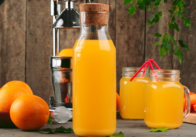 Bottiglia di succo d'arancia con le arance sulla tavola di legno