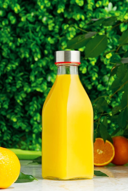 Bottiglia di succo d'arancia fresco con frutta fresca su sfondo verde