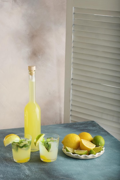 Bottiglia di succo fatto in casa con zenzero e limone su sfondo chiaro Verticale
