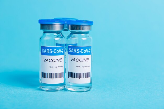 Bottiglia di vaccino contro il coronavirus Covid-19 su sfondo blu.