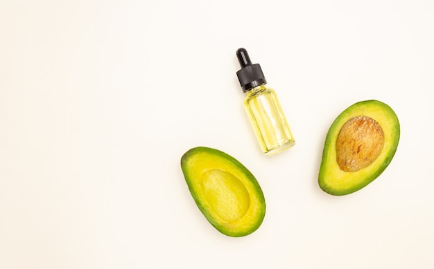 Bottiglia di vetro con pipetta e olio di avocado e frutto di avocado