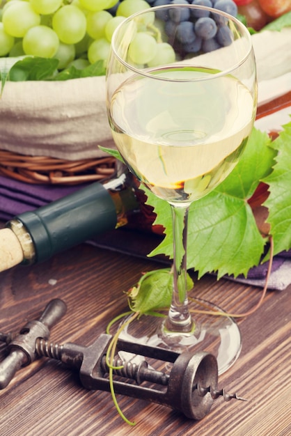 Bottiglia di vetro di vino bianco e uva sulla tavola di legno