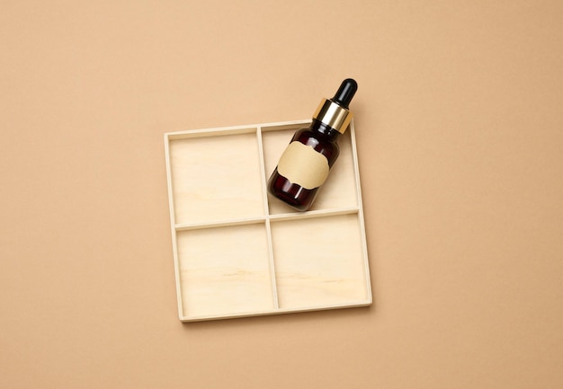Bottiglia di vetro marrone con pipetta a su sfondo marrone chiaro Prodotto cosmetico per la cura della pelle mockup