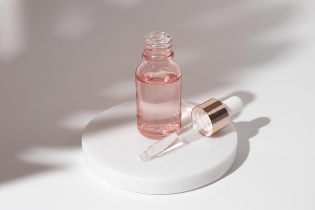 Bottiglia di vetro rosa di gel trasparente liquido cosmetico su sfondo bianco. Flacone contagocce, acido ialuronico, olio, siero, prodotto per la cura della pelle.