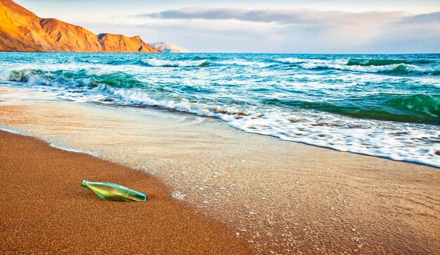 Bottiglia di vetro sulla spiaggia di sabbia al tramonto