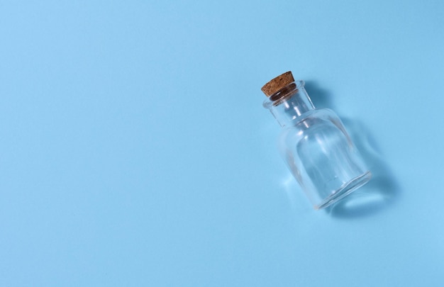 Bottiglia di vetro vuota con tappo di sughero su sfondo blu vista dall'alto