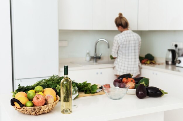 Bottiglia di vino bianco cesto di frutta e verdura sul tavolo della cucina