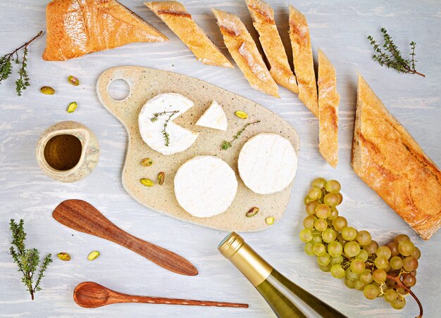 Bottiglia di vino bianco, formaggio, pane e pomodori per la festa a buffet. Il tradizionale francese o italiano entra in piatto. Vista dall'alto