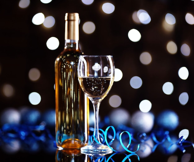 Bottiglia di vino e bicchiere di vino con decorazioni natalizie su sfondo luminoso