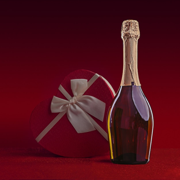 Bottiglia di vino e confezione regalo a forma di cuore con fiocco su glitter