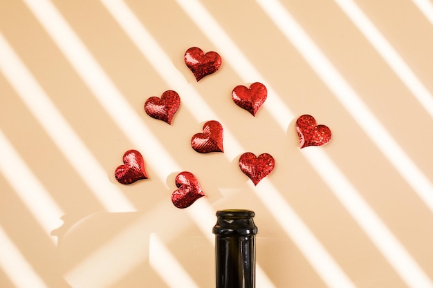 Bottiglia di vino e cuori rossi sopra l'ombra del mattino concetto di inizio di San Valentino