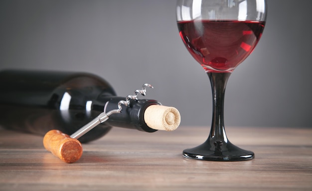 Bottiglia di vino rosso con bicchiere e cavatappi.