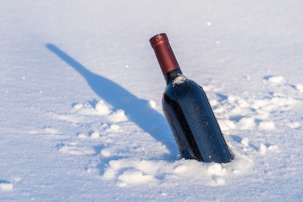 Bottiglia di vino rosso su un letto di neve e sfondo bianco