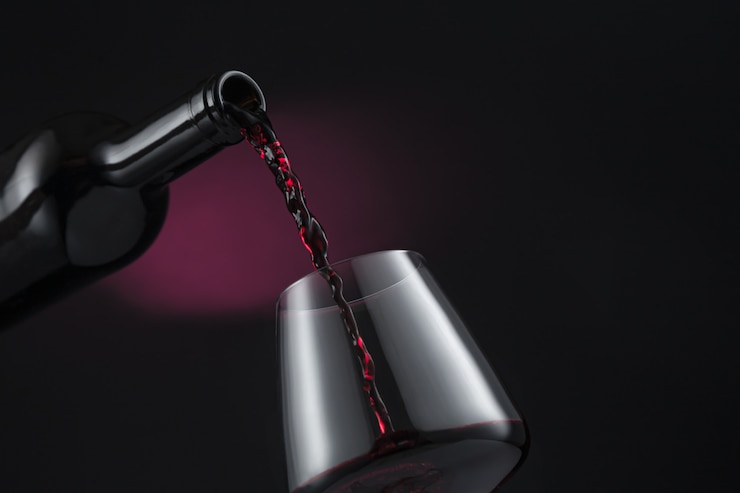 Bottiglia di vino rosso versato nel bicchiere di vino
