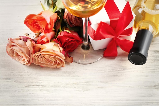 Bottiglia di vino scatole regalo e rose su uno sfondo di legno