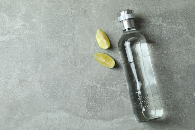Bottiglia di vodka e fette di lime su grigio