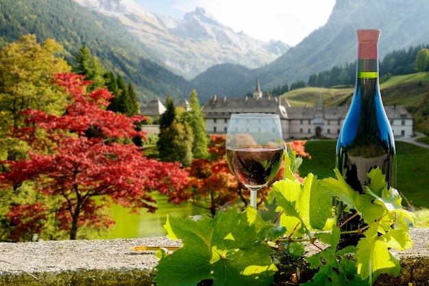 Bottiglia e bicchiere di vino rosso con paesaggio montano autunnale nelle Alpi francesi