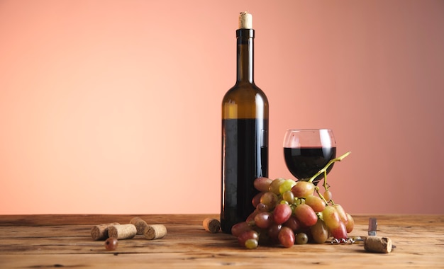 Bottiglia e bicchiere di vino rosso con uve mature