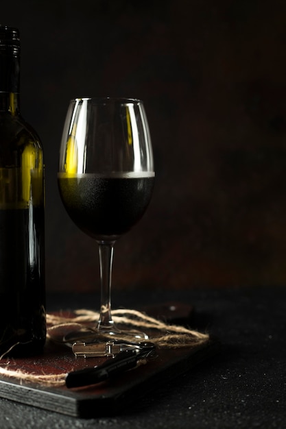 Bottiglia e bicchiere di vino rosso su sfondo nero