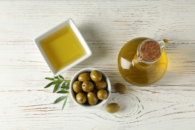 Bottiglia e ciotola con olio d'oliva, ciotola con le olive sulla vista di legno e superiore