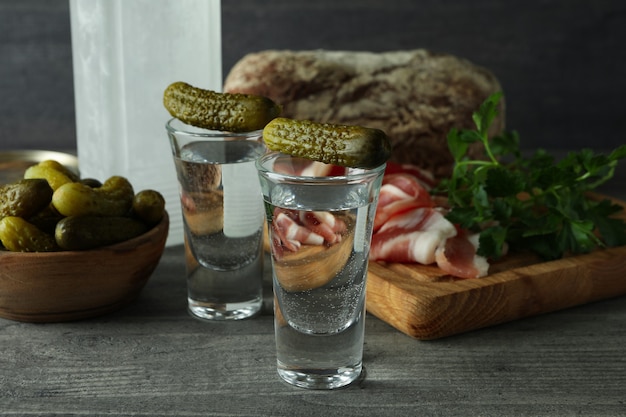 Bottiglia e colpi di vodka e diversi snack sul tavolo grigio