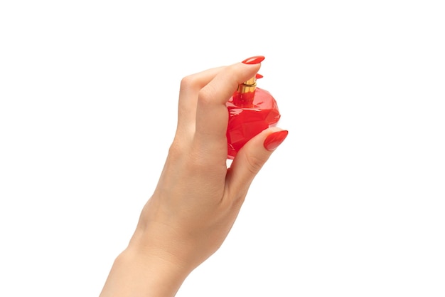 Bottiglia rossa di profumo in mano della donna con chiodi rossi isolati su sfondo bianco