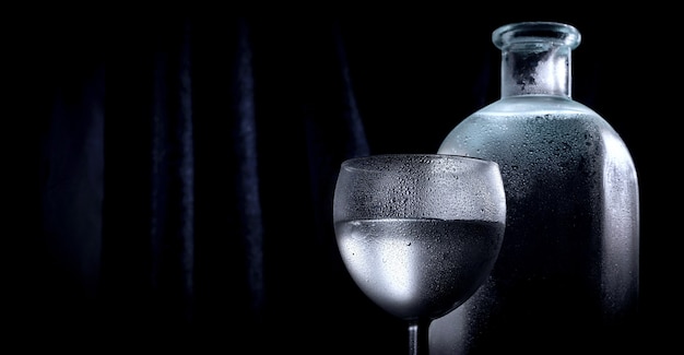 Bottiglia trasparente di vodka o alcol con un bicchierino