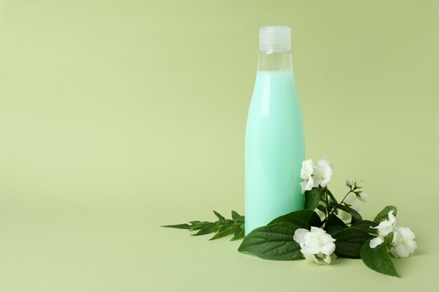 Bottiglia vuota di shampoo e fiori su verde